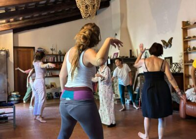 Gruppo di donne danza a piedi nudi in una sala di un casale dalle travi in legno durante un laboratorio sul corpo