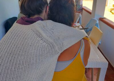 Due donne di spalle abbracciate durante un'attività all'aperto sotto un portico durante un ritiro a Lampedusa