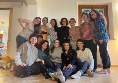 Gruppo di donne sorridenti posa abbracciato in una casa accogliente al termine di un laboratorio di gruppo