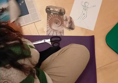 Donna seduta su un tappetino crea un collage accanto a un disegno di figura umana con immagini ritagliate