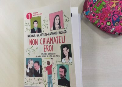 Libro illustrato appoggiato su un tavolo accanto a un astuccio colorato, dettaglio di uno spazio di laboratorio