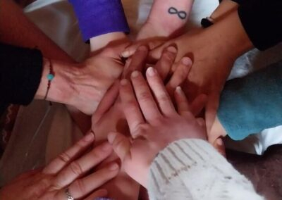 Mani di un gruppo di donne unite al centro di un cerchio, gesto di fiducia e connessione durante un laboratorio